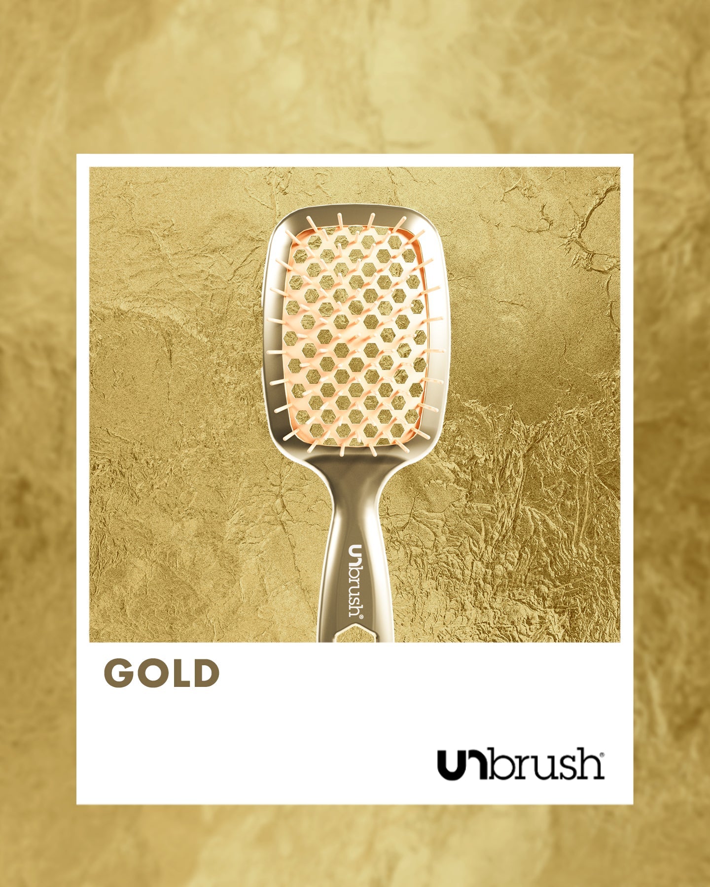 Gold hairbrush with 'unbrush' branding on a textured gold background