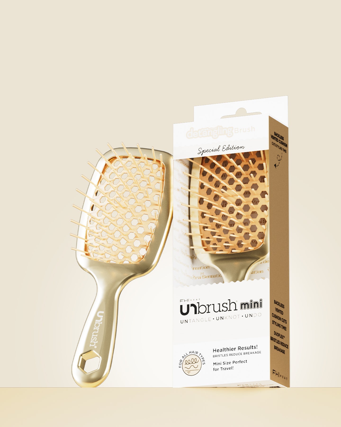 Gold hairbrush with packaging on a beige background