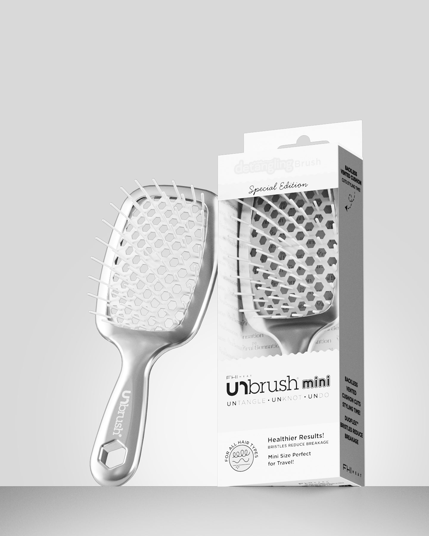 Silver hairbrush with packaging on a light gray background