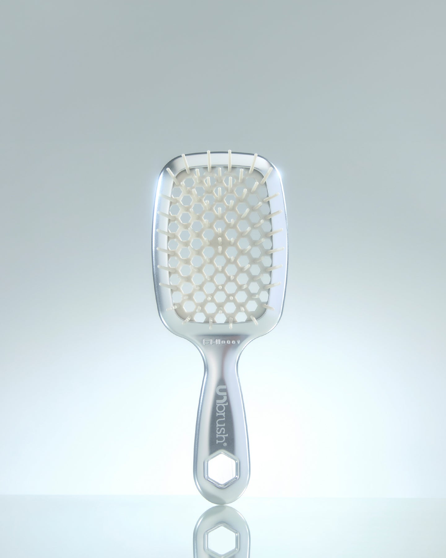 Paddle hairbrush with honeycomb design on a light gray background