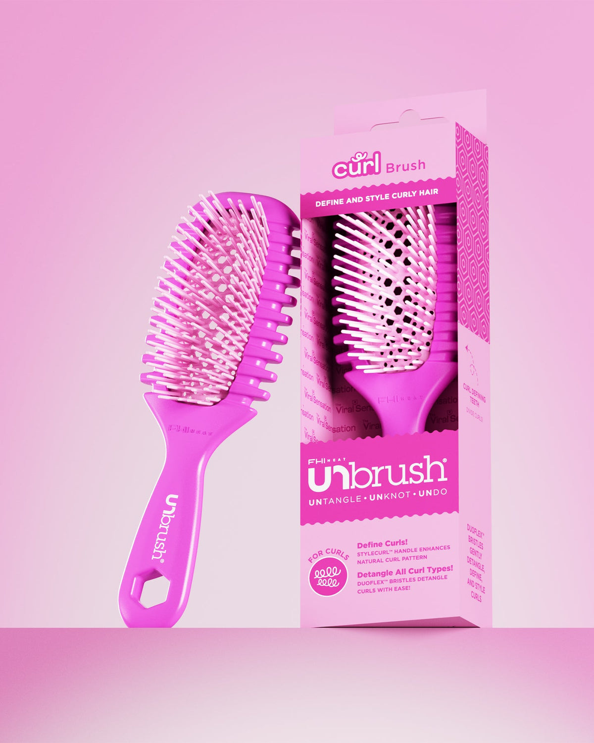 Pink hairbrush with packaging on a pink background