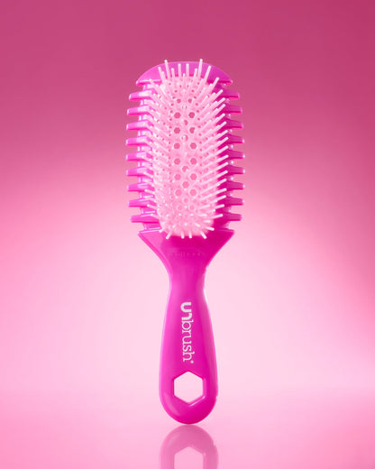 Pink hairbrush with 'unbrush' branding on a pink background
