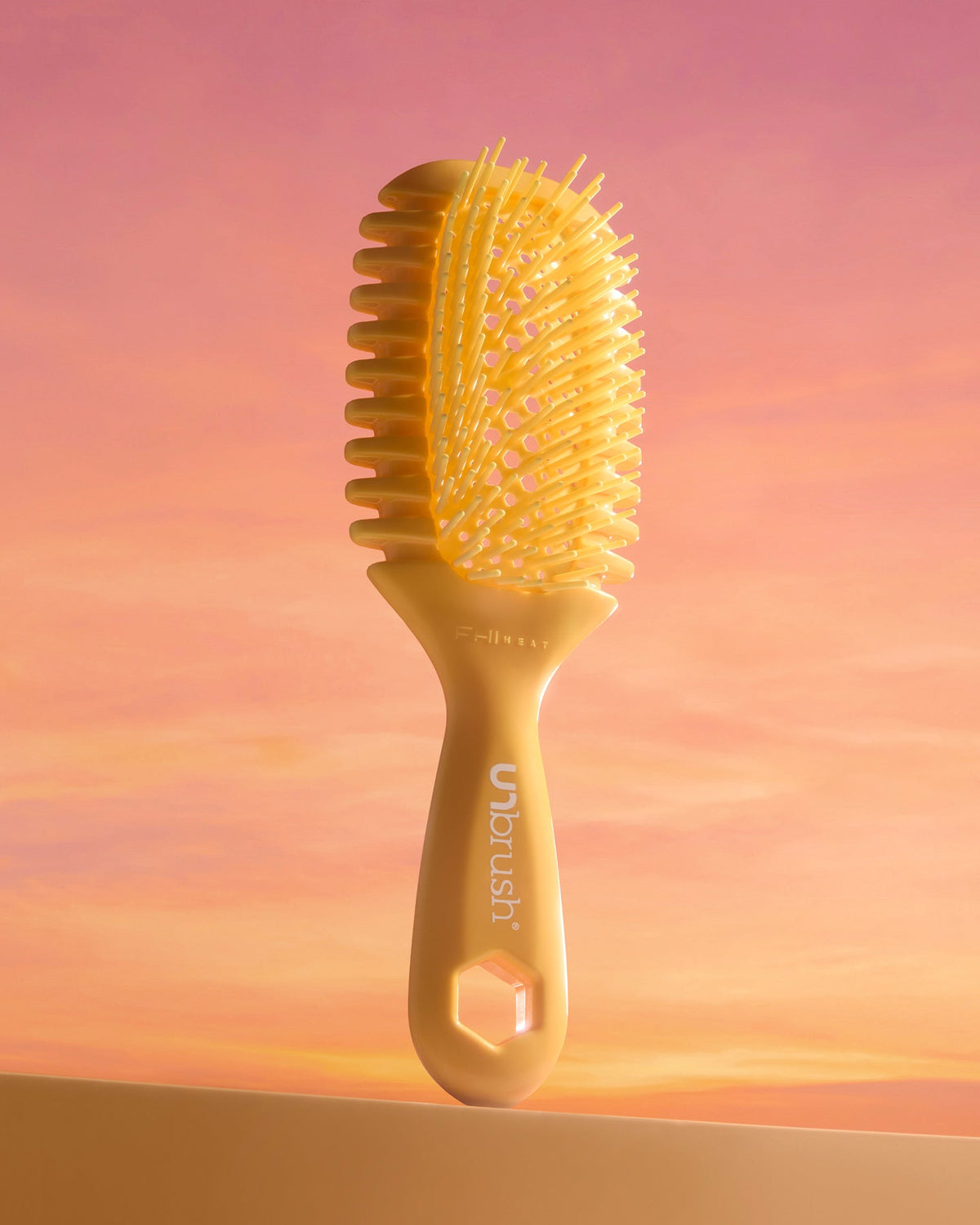 Yellow hairbrush on a pink and orange gradient background