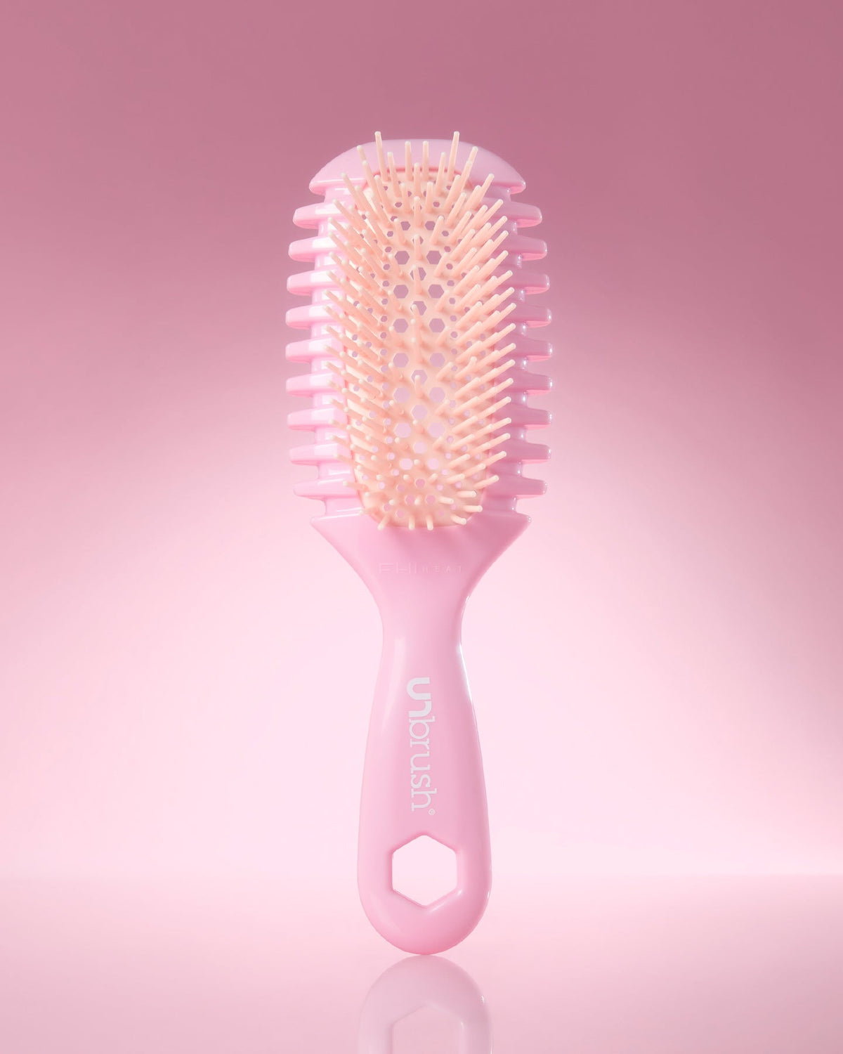 Pink hairbrush with bristles on a pink background