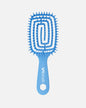 Front view of blue UNbrush hairbrush with flexible spiral bristles and a hexagonal hole in the handle, shown on a off-white background.