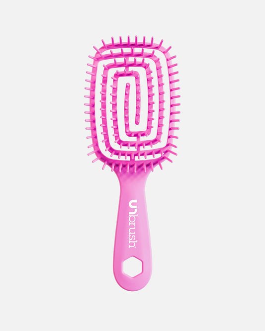 Front view of pink UNbrush hairbrush with flexible spiral bristles and a hexagonal hole in the handle, shown on a off-white background.