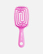 Front view of pink UNbrush hairbrush with flexible spiral bristles and a hexagonal hole in the handle, shown on a off-white background.