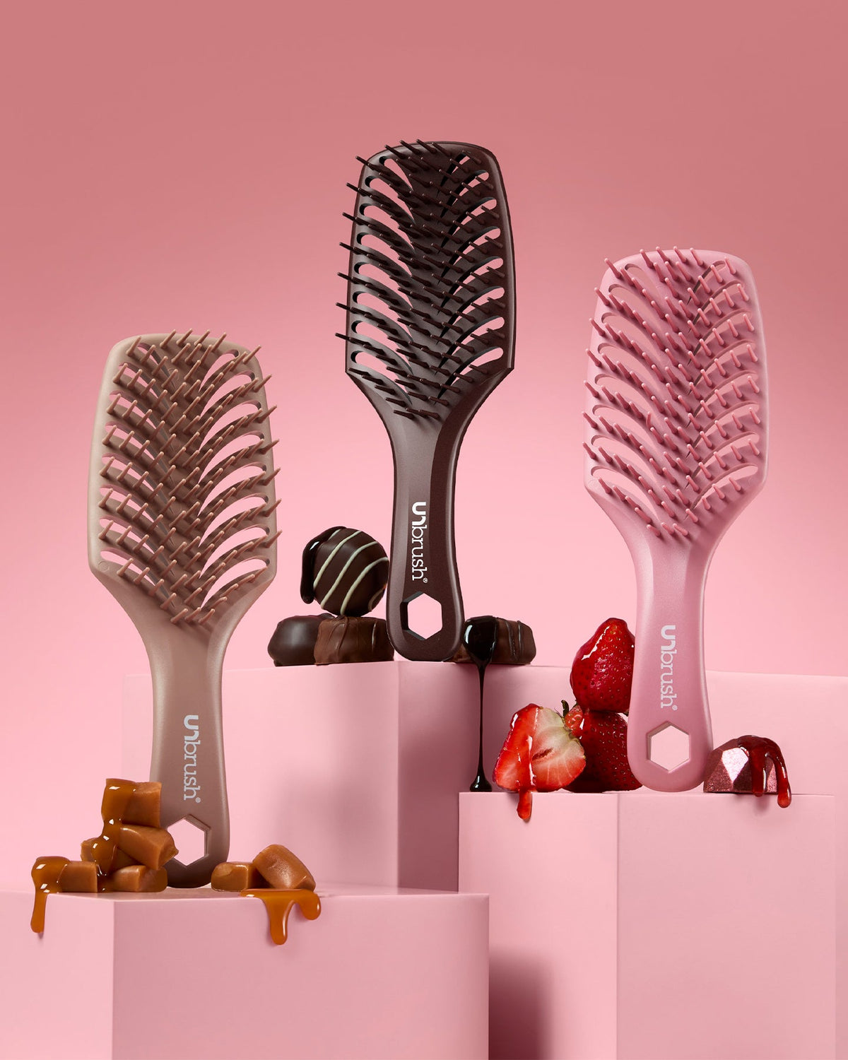 Three hairbrushes on a pink background with treats underneath