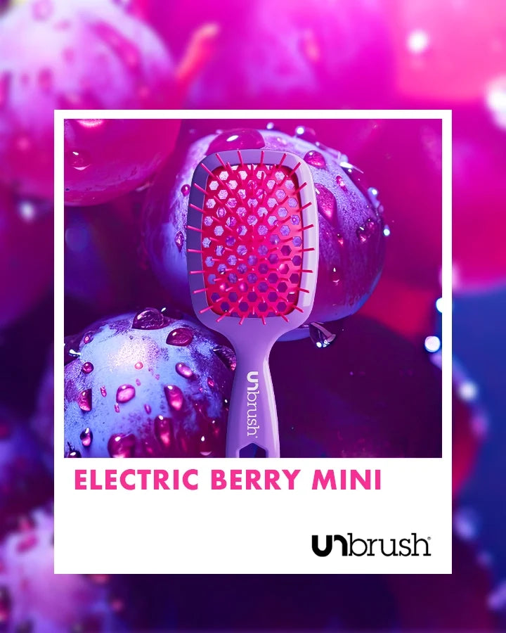 “Electric Berry” Unbrush Mini with vibrant purple hexagon bristles and vibrant pink handle, styled against dark fruit background.