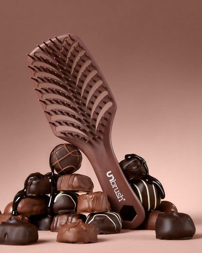 Chocolate hairbrush with candies on a pink background
